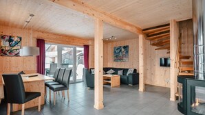 A modern log cabin interior with a dining area, a living room with a sofa and coffee table, and a fireplace. - Chalet Prinz Comfortable Holiday Residence (Murau)