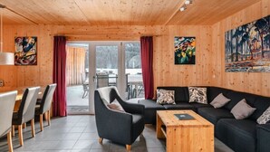 A modern log cabin interior with a dining area, sofa set, and artwork on the walls. - Chalet Prinz Comfortable Holiday Residence (Murau)