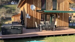 A wooden cabin with a patio area, a trampoline, and a scenic mountain backdrop. - Chalet Prinz Comfortable Holiday Residence (Murau)