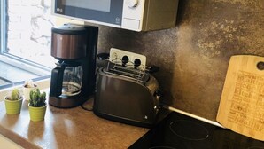A kitchen with a microwave, coffee maker, toaster, and a cutting board on the counter. - Cosy Apartment in Duisburg (Duisburg)
