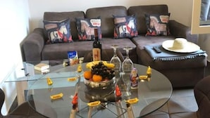 A modern living room with a glass coffee table, leather chairs, a sofa with patterned cushions, and a 'WANTED' poster on the wall. - Cosy Apartment in Duisburg (Duisburg)