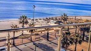 A beach view from a balcony with palm trees and beach umbrellas. - Belvilla by OYO Apartamento 2habitaciones (Fuengirola)