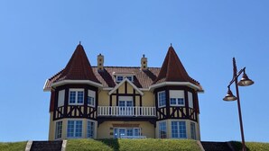 A large, two-story building with a symmetrical facade, multiple windows, and a central balcony. - Schmitz Comfortable Holiday Residence (De Haan)