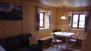 A cozy room with a wooden interior, a sofa, a dining table with chairs, and a painting on the wall. - Characteristic Apartment in Bernbeuren (Bernbeuren)