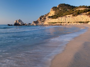 A beach with clear water, a rocky outcrop, and a sandy shore. - Bungalow Orihuela Costa Sunset and Pool (Relleu)