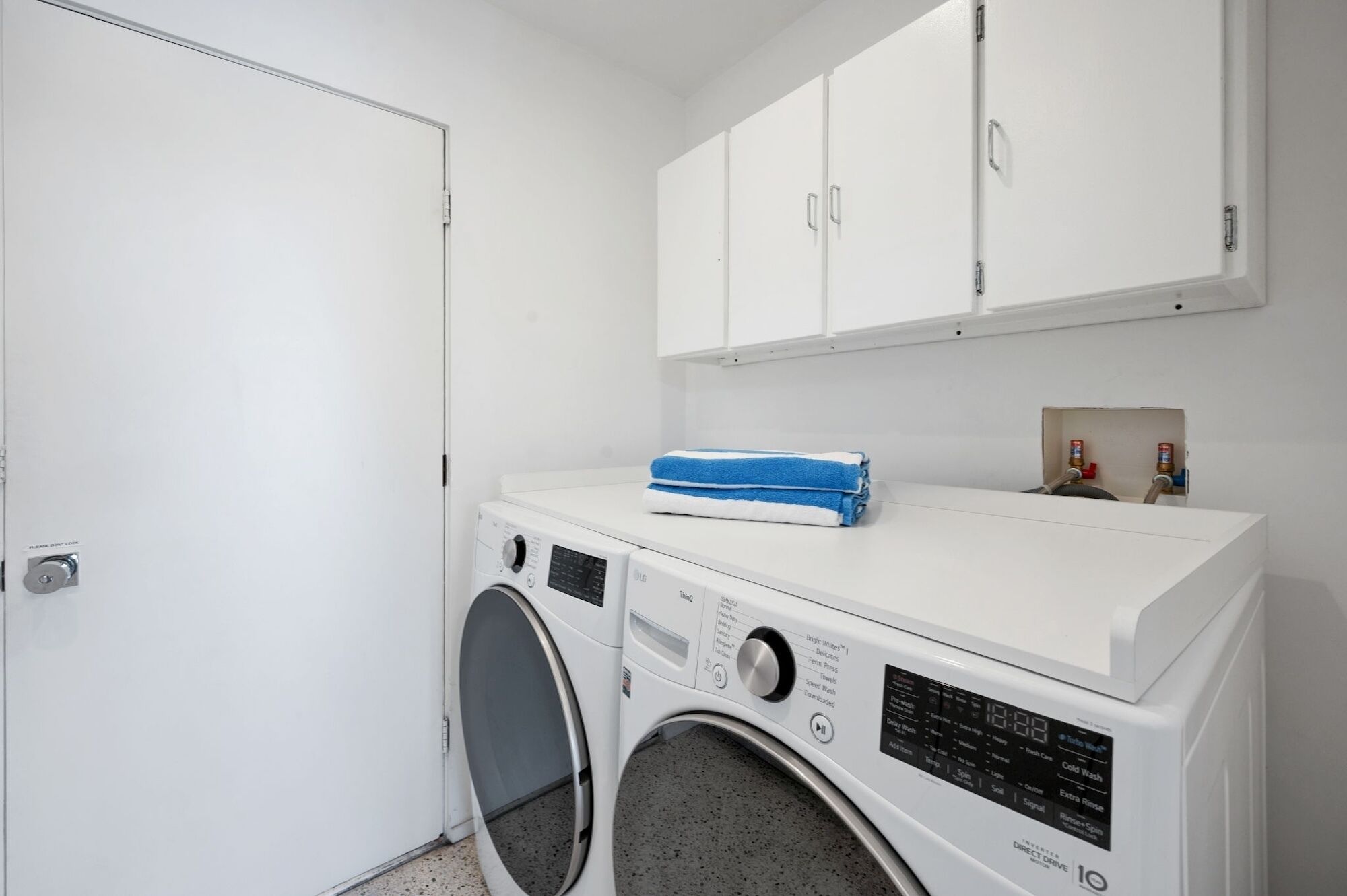 A laundry room with a front-loading washing machine, a dryer, and a cabinet above the dryer.