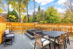 A deck with a table and chairs, surrounded by a wooden fence. - Spacious 6BR Home w/ Jacuzzi, Walk to Big House! (Ann Arbor)