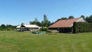 A large grassy field with a building that has a red roof and a white fence. - Tent Lodge in Twijzel Near Town Center (Twijzel)