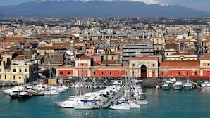 A coastal cityscape with a prominent snow-capped mountain in the background, a marina with numerous boats, and historic buildings with red and white facades. - Pool House Giulia Comfortable Holiday Residence (Letojanni)