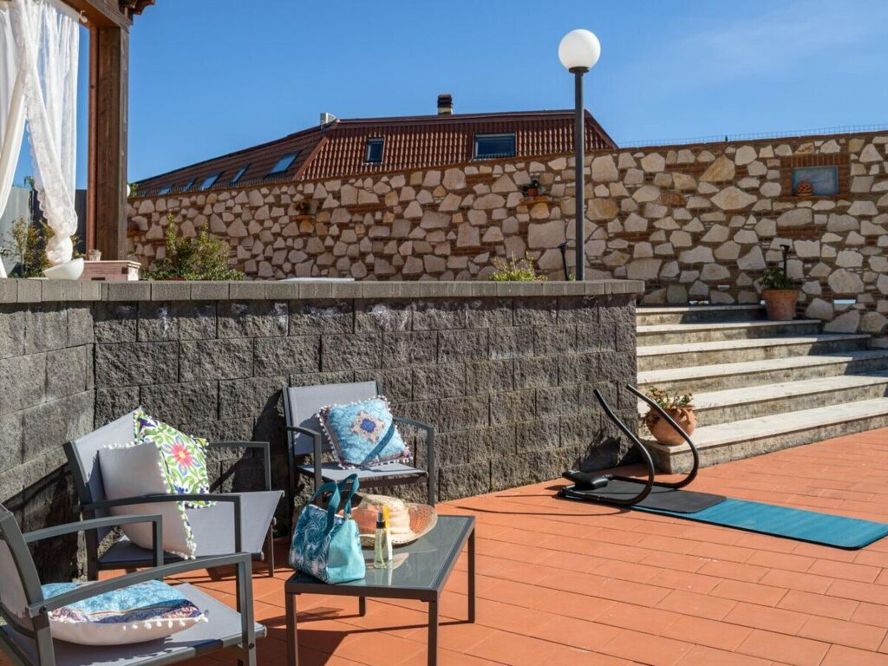 Una terrazza con posti a sedere all'aperto, un muro in pietra e vista su un edificio in pietra con tetto in tegole.