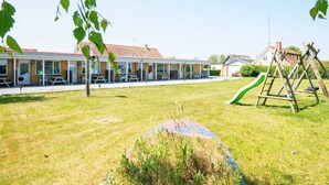 A building with a covered patio area, outdoor seating, and a playground with a slide. - Seaside Retreat in Kegnaes - By Traum Ferienwohnungen (Sydals)
