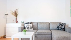 A modern living room with a grey sectional sofa, a white coffee table, and a small white cabinet. - Seaside Retreat in Kegnaes - By Traum Ferienwohnungen (Sydals)
