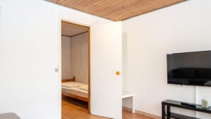 A modern living room with a wooden ceiling, a flat-screen TV, a black TV stand, and a grey sofa. - Seaside Retreat in Kegnaes - By Traum Ferienwohnungen (Sydals)