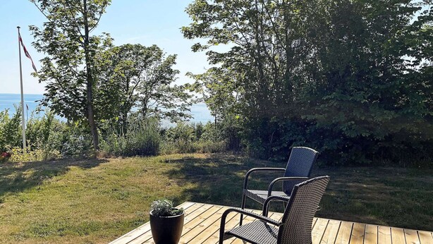 A wooden deck with two wicker chairs and a potted plant. - 4 Person Holiday Home in Ronne (Ronne)