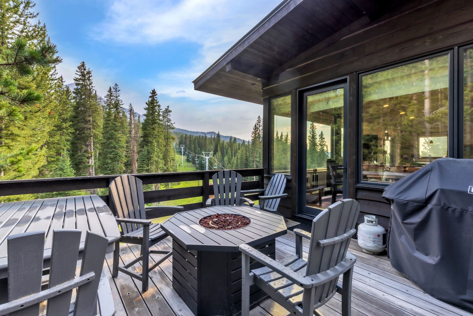 Une terrasse extérieure avec une table et des chaises, donnant sur une zone boisée et offrant une vue sur une montagne au loin.