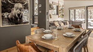 A dining area with a wooden table set for six, surrounded by leather chairs.
