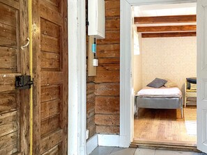 A wooden door leading to a room with a bed, a bedside table, and a lamp. - 5 Person Holiday Home in Valdemarsvik (Valdemarsvik)