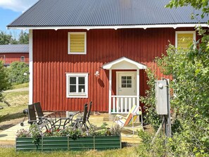 A red wooden house with a porch, a small window, and a door. - 5 Person Holiday Home in Valdemarsvik (Valdemarsvik)