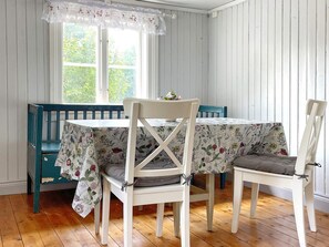 A dining area with a table and chairs, a bench, and a window with a view of greenery. - 5 Person Holiday Home in Valdemarsvik (Valdemarsvik)