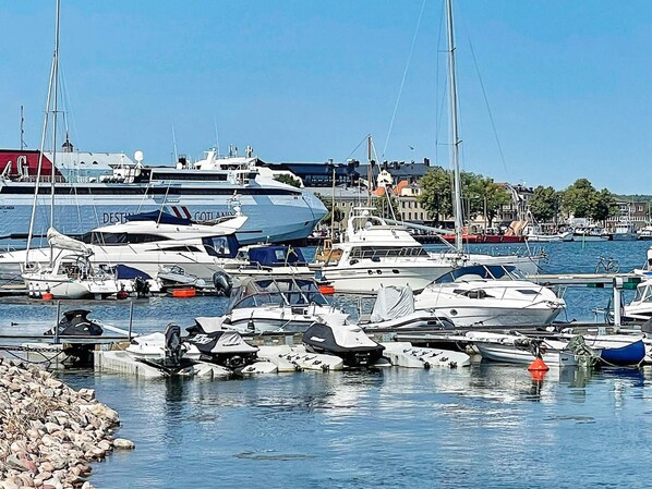 A marina with various boats docked, a large cruise ship in the background, and buildings along the waterfront. - 5 Person Holiday Home in Valdemarsvik (Valdemarsvik)