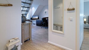 Un intérieur moderne avec un escalier, un espace de vie doté d’un téléviseur et un grand miroir.