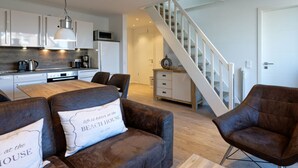 Une cuisine moderne avec des meubles blancs, une table à manger et un escalier menant à un autre niveau.
