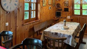 Un interior de madera con una mesa de comedor, sillas, un reloj y ventanas.