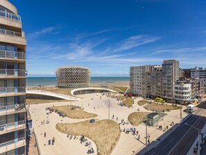 Une zone urbaine côtière caractérisée par un bâtiment sphérique remarquable, une promenade animée et des immeubles modernes.