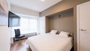 Een moderne slaapkamer met een groot bed, een bureau en een stoel.