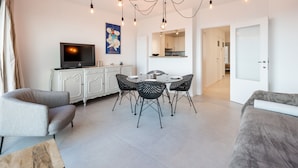 Un salon moderne avec un coin repas, un téléviseur et une cuisine en arrière-plan.