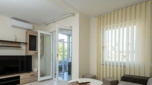 A modern living room with a flat-screen TV, a sofa, a coffee table, and a sliding glass door leading to an outdoor area. - Donatella -apt 1- 10m van het Strand (Medulin)