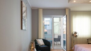 A modern bedroom with a bed, a chair, a floor lamp, and a sliding glass door leading to a balcony. - Donatella -apt 1- 10m van het Strand (Medulin)