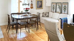 Un comedor con mesa y sillas de madera, un sofá y un jarrón decorativo con flores.
