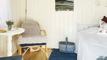 Un dormitorio con una cama, una silla, una mesita y una lámpara de pie.