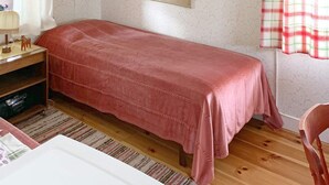 Un dormitorio con una cama individual, un escritorio de madera, una silla y una ventana con cortinas.