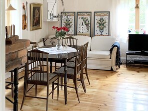 A dining area with a wooden table and chairs, a white sofa, and a television. - 3 Person Holiday Home in Grangarde (Grangarde)