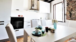 A modern kitchen with white cabinets, a built-in oven, and a stone wall. - Belvilla by OYO Appartemento Chardonnay (Santa Giustina)