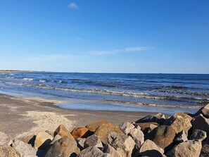A beach with waves, a clear sky, and large rocks in the foreground. - 5 Star Holiday Home in Albaek (Aalbaek)