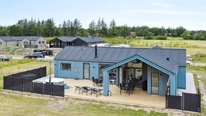 Un bâtiment moderne doté d’une grande terrasse, d’un espace salon extérieur et d’un patio couvert.