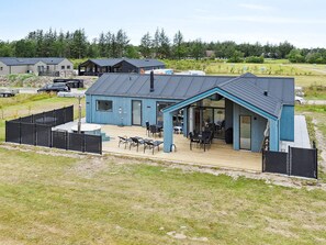 A modern building with a large deck, outdoor seating, and a covered patio area. - 5 Star Holiday Home in Albaek (Aalbaek)
