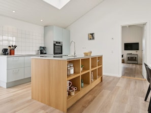 A modern kitchen with a central island, white cabinetry, and a wooden floor. - 5 Star Holiday Home in Albaek (Aalbaek)