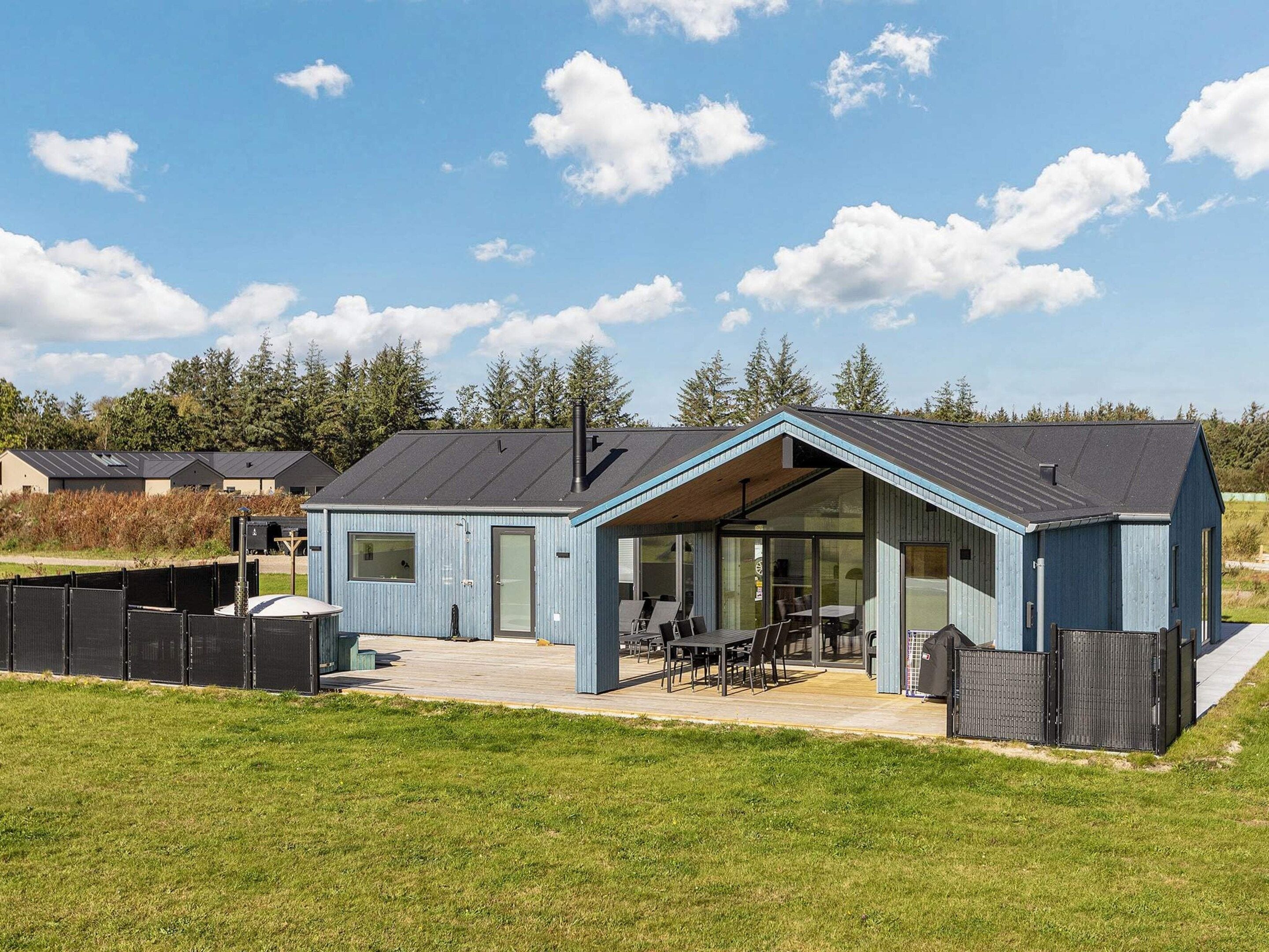 A modern house with a large patio, a covered outdoor seating area, and a fenced yard.