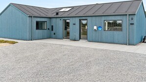 Un bâtiment bleu avec un toit en pente, une porte et une fenêtre.