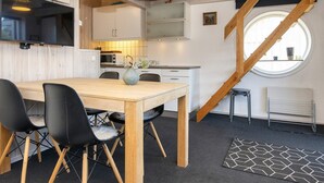 Een moderne keuken met houten kastjes, een eettafel met stoelen en een groot raam met uitzicht.