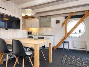 Een moderne keuken met houten kastjes, een eettafel met stoelen en een groot raam met uitzicht.