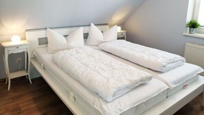 A twin bed with white bedding in a room with a sloped ceiling. - Achtern Diek Modern Retreat (Schönberg)