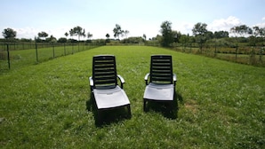 Two black lounge chairs in a grassy field with a fence and trees in the background. - Achtern Diek Modern Retreat (Schönberg)