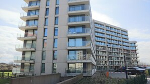 A multi-story residential building with balconies, large windows, and a flat roof.