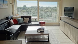 A modern living room with a black leather sofa, a coffee table, and a television on a stand.