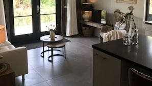 A cozy room with a dining area, a small table with a lamp, and a view through a glass door. - Holiday Apartment Salt and Dunes (Schoorl)